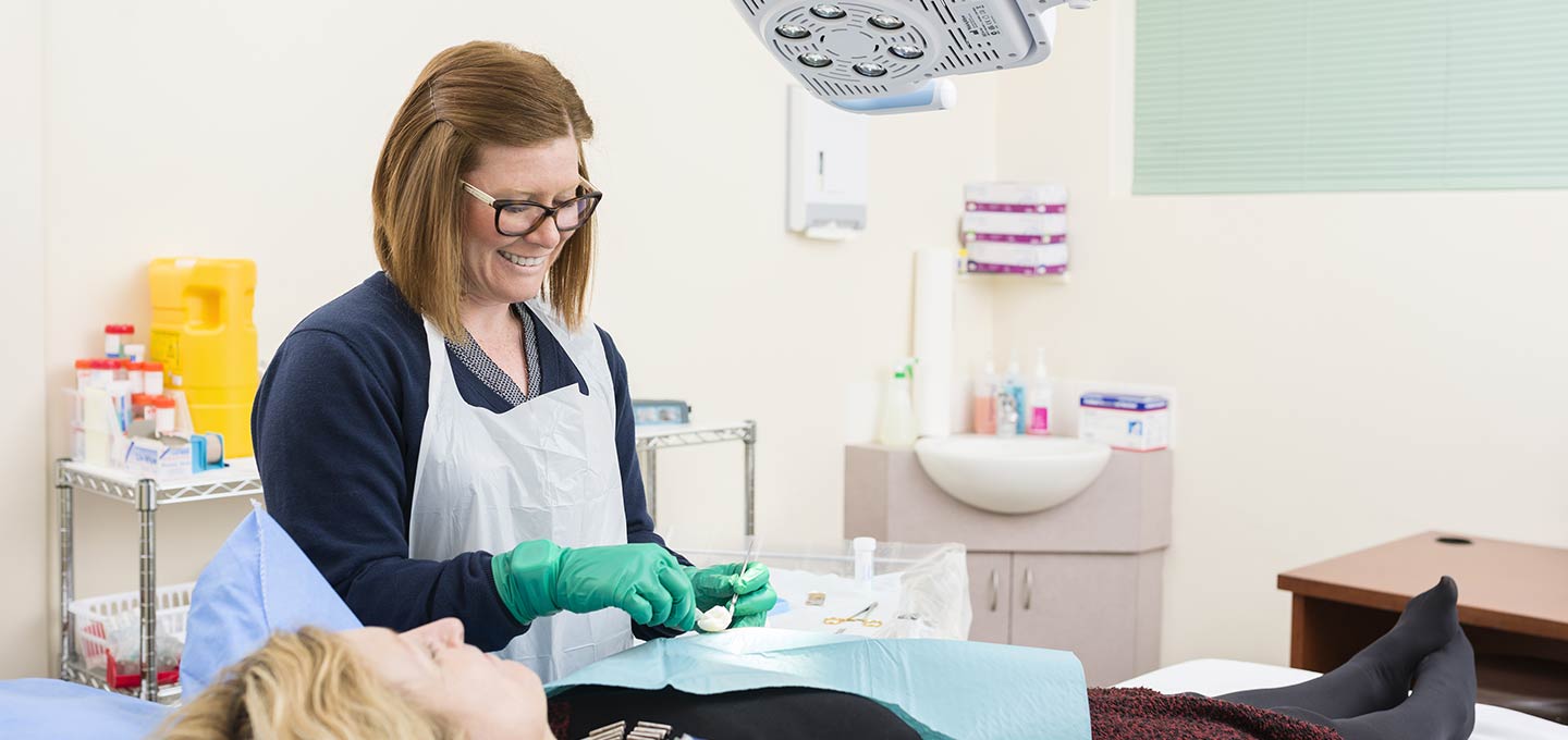 A nurse preparing a patient for a clinical procedure in a treatment room