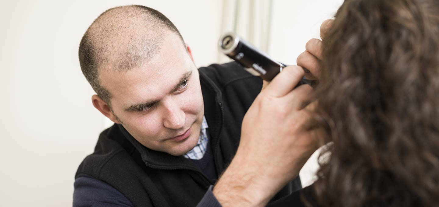 A doctor examining a patient’s ear.